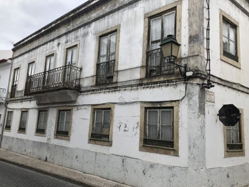 Fachada da pensão Patio Da Villa em Coruche, Portugal, com paredes brancas envelhecidas e varandas em ferro forjado