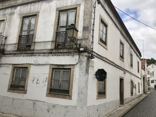 Fachada histórica branca da pousada Patio Da Villa em Coruche, Portugal, com paredes envelhecidas e janelas tradicionais