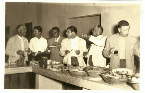 Seis homens em ternos claros aproveitando drinks e petiscos em encontro social na pousada Patio Da Villa em Coruche.