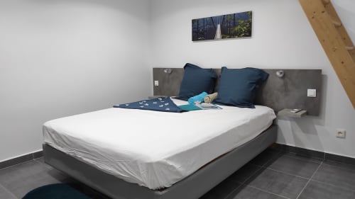 Chambre élégante de la villa Kaz A Bibi avec lit blanc, oreillers anthracite, tête de lit grise et œuvres paysagères à Sainte-Rose