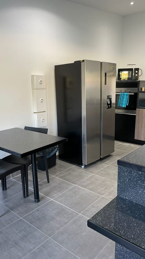 Cuisine moderne de la villa Kaz A Bibi, Sainte-Rose, avec électroménagers en acier inoxydable, plan de travail noir et coin repas