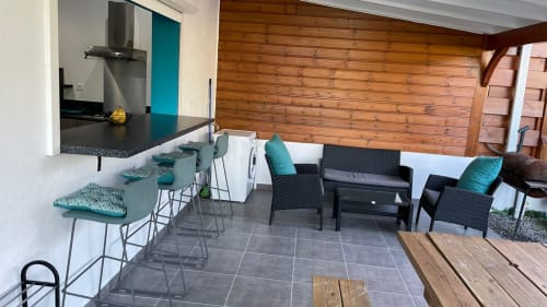 Espace repas et salon moderne à Kaz A Bibi à Sainte-Rose avec plafonds en bois, sièges en turquoise et cuisine