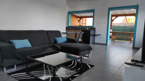 Salon moderne de la villa Kaz A Bibi à Sainte-Rose avec canapé noir, accents turquoise et portes vitrées sur balcon