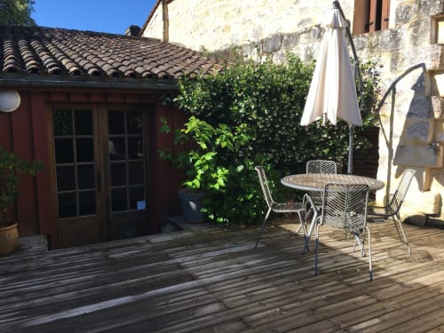 Patio ombragé du Sous Les Marronniers B&B à Petit Palais Cornemps avec table de salle à manger et parasol