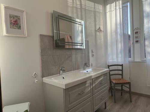 Modernes Badezimmer im Château Ségot mit Doppelwaschtisch, Spiegel und natürlichem Licht von den Fenstern
