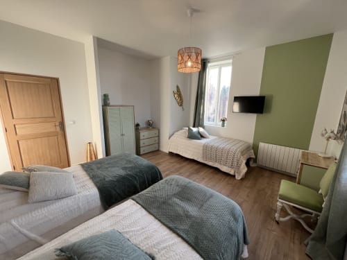 Helles Familienzimmer im Château Ségot mit zwei Betten, grüner Akzentwand, Fernseher und Gartenblick in Neuilly-le-Réal