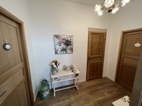 Eleganter Flur im Familienraum des Château Ségot mit Holztüren, weißem Konsolentisch und Blumendekoration
