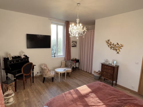 Elegantes Familienzimmer im Château Ségot mit Bett, Sitzbereich, TV, Kristalllüster und Gartenblick in Neuilly-le-Réal
