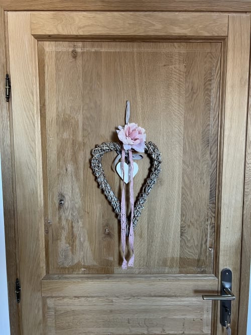 Herzförmiger geflochtener Kranz mit rosa Blumendekoration an der Holztür des Château Ségot, Neuilly-le-Réal