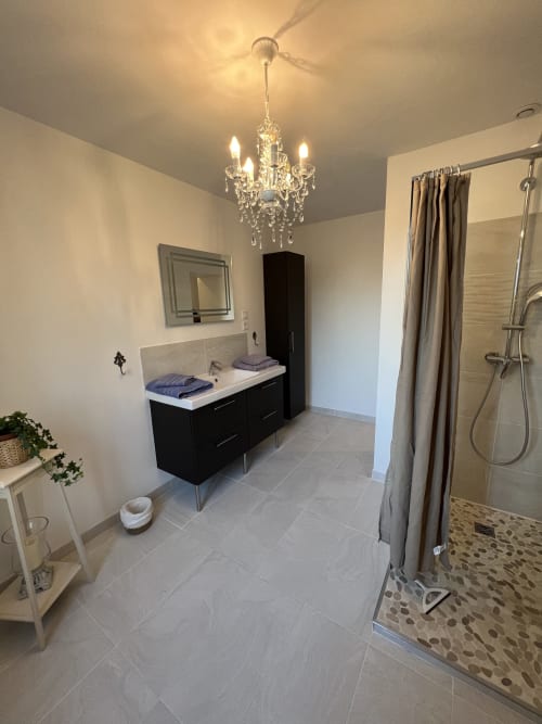 Modernes Badezimmer im Château Ségot mit schwarzem Waschtisch, Kronleuchter, begehbarer Dusche und Fußbodenheizung im Zimmer Gabrielle Robinne