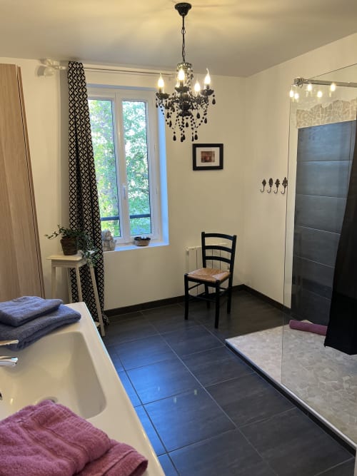Gabrielle-Chanel-Zimmer im Château Ségot in Neuilly-le-Réal mit Badezimmer, schwarzem Kronleuchter und Sitzbereich mit Sessel