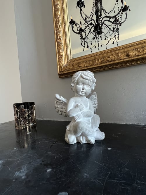 Weiße Cherubstatue mit dekorativen Elementen auf schwarzer Marmoroberfläche im Gabrielle-Chanel-Zimmer des Château Ségot