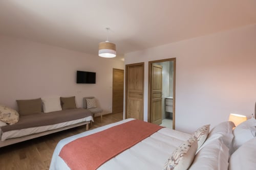 Chambre spacieuse à La Vallee Joly B&B au Vast avec lit, coin salon, portes en bois et luminaires suspendus modernes