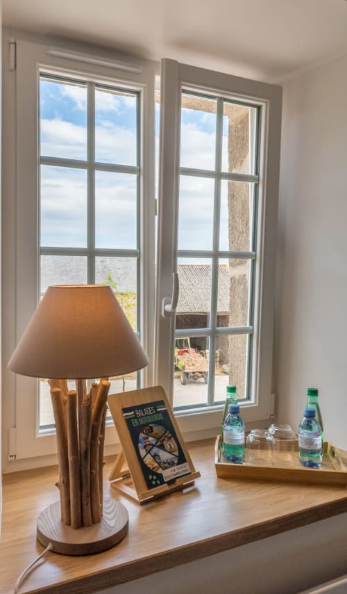Bureau en bois avec lampe et bouteilles d'eau à La Vallee Joly, vue sur la campagne du Vast, France