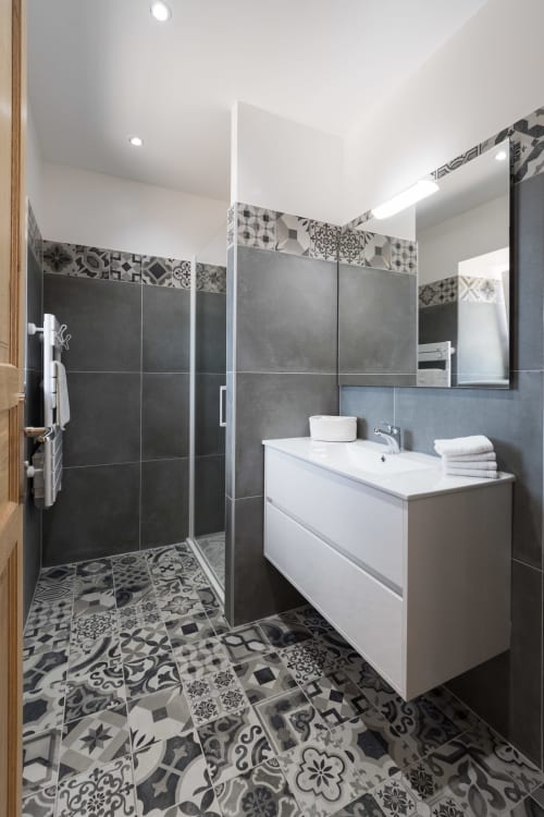 Salle de bain moderne à la Vallée Joly B&B au Vast, France avec douche à l'italienne, vasque blanche et carrelage géométrique