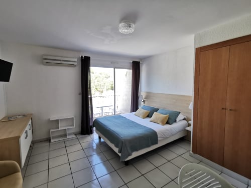 Chambre moderne à la Résidence Saint Michel à L'île Rousse avec accents bleus, accès balcon, climatisation et TV écran plat
