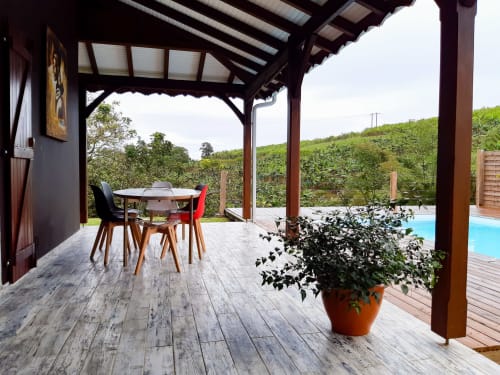 Patio de la Villa Tourmaline avec table de salle à manger, pergola couverte, vue sur la piscine et paysage montagneux luxuriant de la Martinique au Lorrain