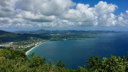 Vue panoramique côtière de Le Lorrain, Martinique avec baie turquoise, plage de sable, collines verdoyantes et ciel nuageux