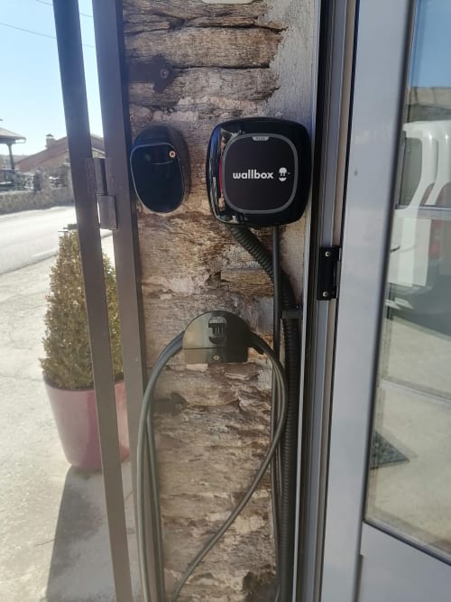 Wallbox EV charging station mounted on brick wall at Casa Rural La Perla, Hiendelaencina