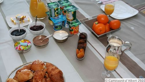 Petit-déjeuner à la Campagne d'Albert B&B Marseille : croissants, oranges fraîches, jus et tartinades sur table blanche