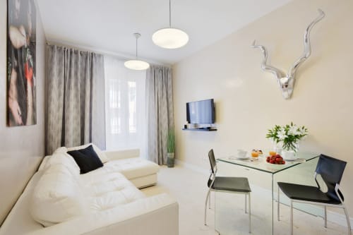 Soggiorno moderno in Petra Apartments Roma con divano bianco, tavolo da pranzo in vetro, TV a parete e design contemporaneo