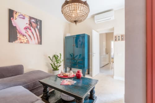 Elegante soggiorno moderno degli Apartamenti Petra Roma con mobile blu, divano grigio, opere d'arte decorative e soffitto in tessuto intrecciato