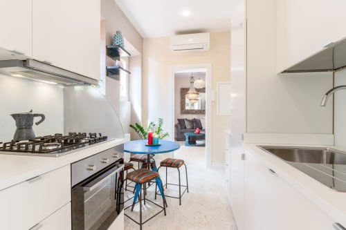 Cucina moderna con fornello a gas, tavolo bar blu e lavello in acciaio inossidabile negli Appartamenti Petra a Roma