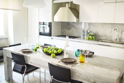 Cucina moderna con top in marmo, armadi bianchi e zona pranzo con mele verdi a Petra Apartments, Roma