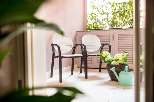 Balcone privato dell'Apartment Petra a Roma con due sedie, fiori in vaso e annaffiatoio con vista sulla città