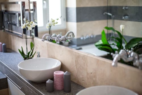 Bagno Petra Apartments Roma con lavabo bianco a catino, orchidee, candele e rubinetti cromati