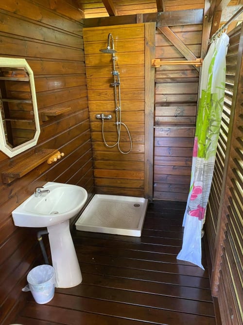 Salle de bains rustique à Les Hauts De Deshaies avec lavabo sur pied, douche et équipements traditionnels