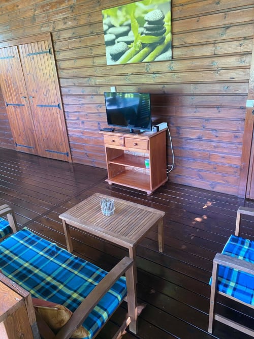 Spacieux salon en bois aux Hauts De Deshaies avec téléviseur, mobilier et sièges à carreaux bleus