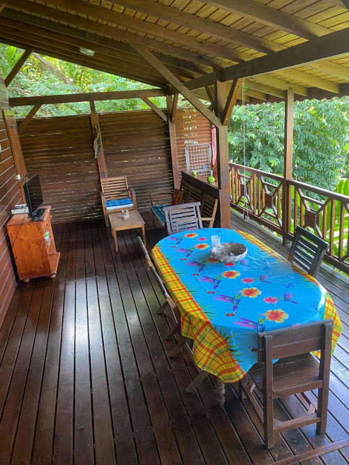 Terrasse couverte aux Hauts de Deshaies avec table à manger, chaises et vue tropicale à Deshaies, Guadeloupe