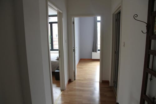Corridoio luminoso nell'appartamento Courcelles con pavimento in legno e numerose porte che conducono alle camere