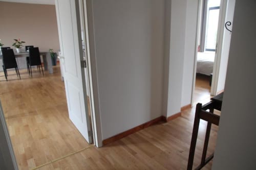 Corridoio di appartamento moderno con pavimenti in legno, pareti bianche e zona living open-plan a Courcelles, Belgio