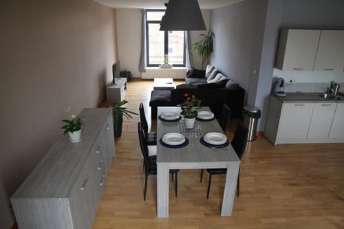 Cuisine et salle à manger modernes avec table dressée, canapé noir et vue sur la ville à Courcelles, Belgique