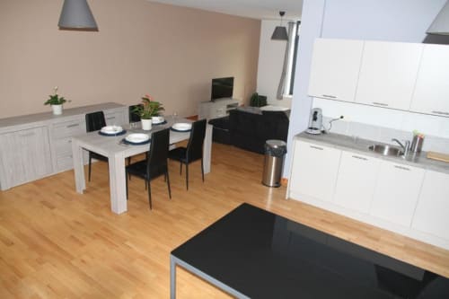 Cucina a vista e area dining nell'appartamento Courcelles con mobili bianchi, tavolo da pranzo e pavimenti in legno.