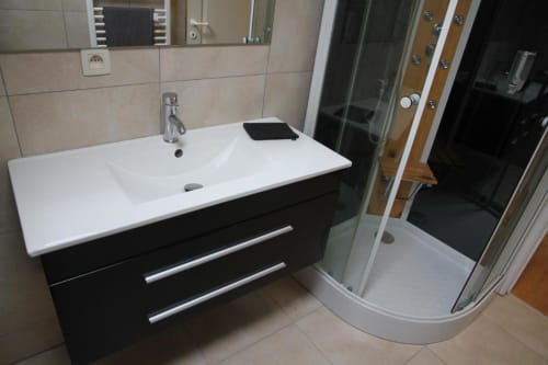 Bagno moderno presso Appartements Courcelles con mobile nero, lavabo bianco e doccia in vetro a Courcelles, Belgio