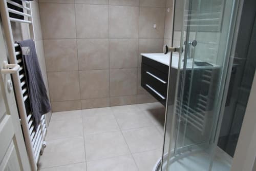 Bagno moderno nell'appartamento Courcelles con doccia, mobile nero, scaldarutto e piastrelle beige