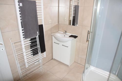 Modern bathroom at Appartements Courcelles with white sink vanity, towel rack, and shower enclosure