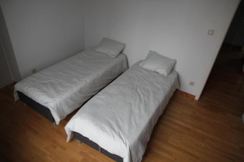 Two single beds with gray linens and pillows in a bright bedroom at Appartements Courcelles, Courcelles, Belgium