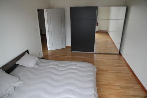 Spacious bedroom at Appartements Courcelles in Courcelles with wooden flooring, bed, wardrobe, and mirror doors