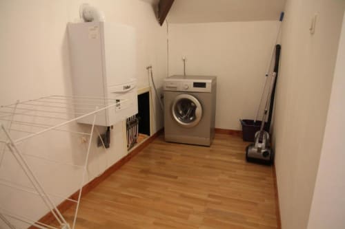 Laundry room in Courcelles apartment with washing machine, dryer, clothes rack and cleaning supplies