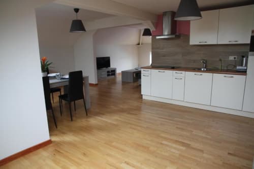 Cuisine ouverte et salle à manger modernes dans l'appartement Courcelles avec meubles blancs, parquet et espace de vie