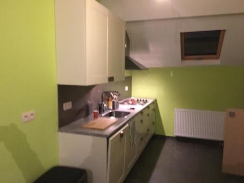 Cozinha moderna no apartamento de Courcelles com paredes verde-lima, armários brancos e bancadas escuras