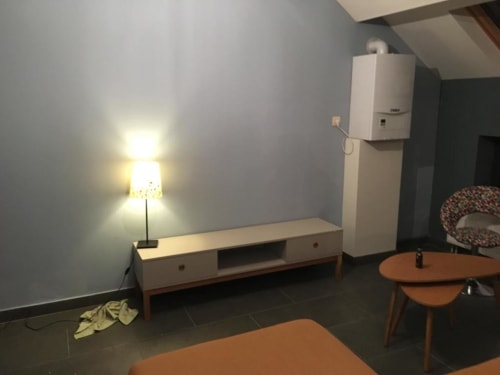 Sala de estar do apartamento 166/2 com TV, luminária, caldeira e móveis modernos em Courcelles