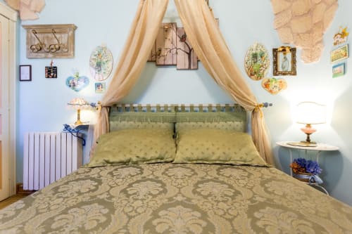 Elegante letto a baldacchino con tende color crema nella Camera Layla di Dormire Assisi B&B, Assisi, con pareti decorate in stile d'epoca