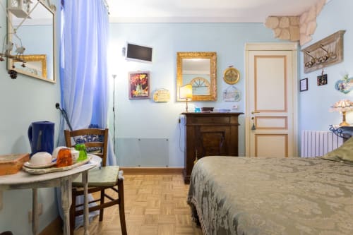 Accogliente camera da letto presso Dormire Assisi B&B con pareti azzurre, letto in legno, specchio antico e arredi d'epoca
