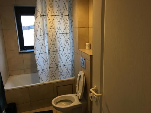 Modern bathroom with bathtub, shower, toilet, and window at Appartements Courcelles apartment in Courcelles