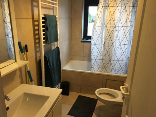 Modern bathroom in Courcelles apartment with shower, toilet, sink, and heated towel rack